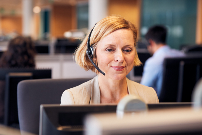 woman wearing headset working at desktop computer smiling