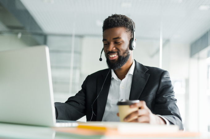 man sitting at desktop wearing headset smiling