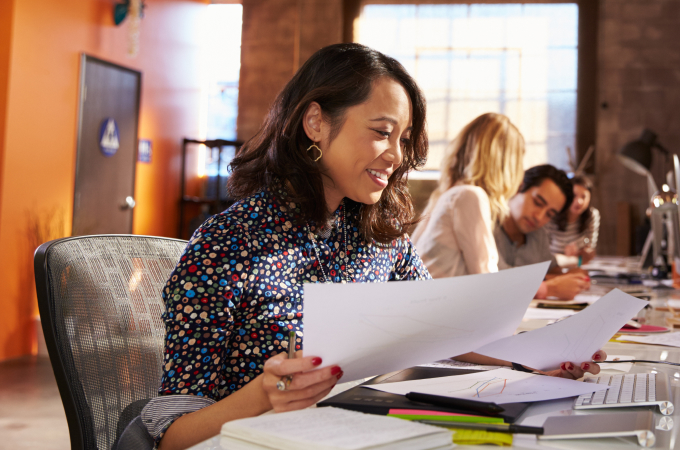 woman looking at paperwork sitting at desk