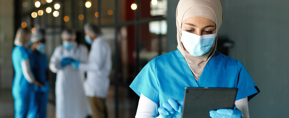 Nurse wearing facemask looking at tablet
