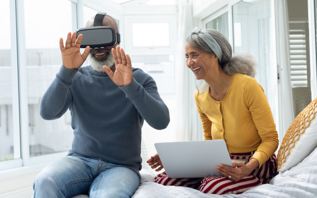 Man with virtual headset on and older woman sitting next to him