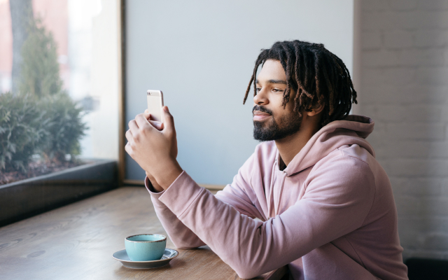 Man looking at mobile with coffee