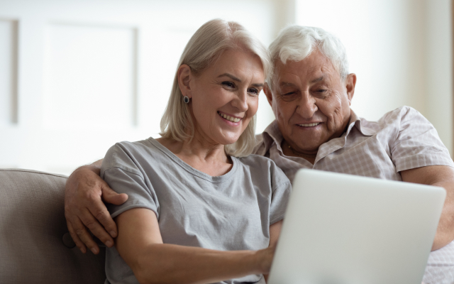 Older couple sitting together, looking at laptop screen